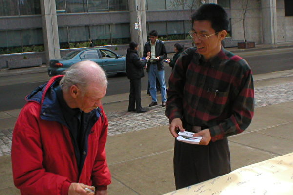 梁彪先生(右)在向路人讲述妈妈的故事(大纪元) 梁彪先生(右)在向路人讲述妈妈的故事(大纪元)