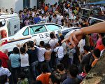 图：贵州628瓮安事件现场。民众掀翻警车。（新唐人图片）
