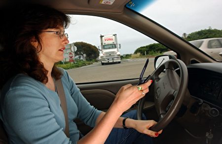 最新研究發現，開車發送簡訊的危險性遠高於撥打手機，幾乎等同於酒後駕車。 圖為加州一名婦女於駕駛中正在使用手機。(David McNew/Getty Images)