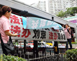 穿著粉紅色制服的「香港青年關愛協會」中共幫兇，用帶來的橫幅掩蓋法輪功學員的橫幅，故意挑釁香港法輪功學員。（攝影：潘在殊／大紀元）