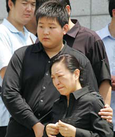 罗京的妻子刘继红难掩悲伤,站立者为罗京的的儿子罗疏桐。(AFP) 罗京的妻子刘继红难掩悲伤,站立者为罗京的的儿子罗疏桐。(AFP)