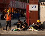 由於西方市場需求不振，和東南亞工廠的興起，雙重擠壓、衝擊了中國工廠，工廠倒閉、外移，失業工人將引發嚴重社會問題。圖為2012年5月，北京市某工地工人在門口休息的場面。（Ed Jones/AFP/GettyImages）