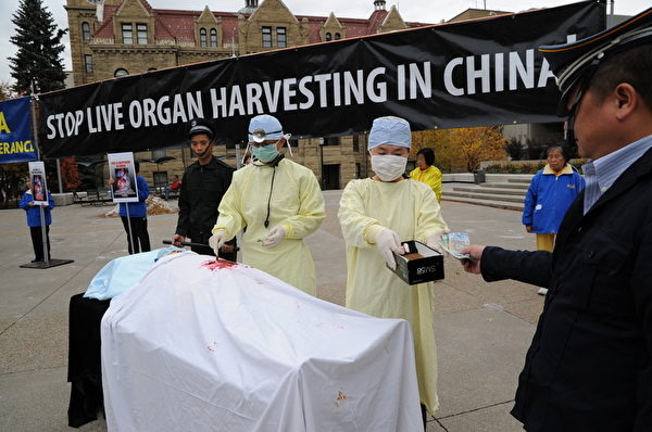 圖:10月16日中午,加拿大卡爾加里法輪大法學會的部分學員,與當地政要和民主黨人士在市政府大樓前舉行集會,譴責中共活摘器官。圖為中共活摘器官牟取暴利的模擬表演。(攝影:吳偉林/大紀元) 圖:10月16日中午,加拿大卡爾加里法輪大法學會的部分學員,與當地政要和民主黨人士在市政府大樓前舉行集會,譴責中共活摘器官。圖為中共活摘器官牟取暴利的模擬表演。(攝影:吳偉林/大紀元)