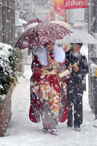 2013年1月14日，东京都心降下今年冬天第一场雪。图为身穿和服的20岁妙龄女子前往参加东京的成年仪式。（Yoshikazu TSUNO/AFP）