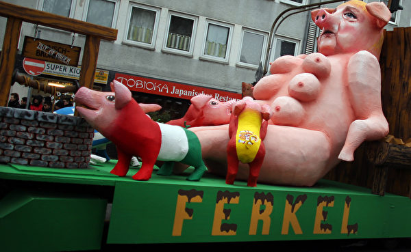 默克尔被刻画成母猪，欧元危机国意大利等纷纷上来吸奶。（OLIVER BERG/AFP/Getty Images）