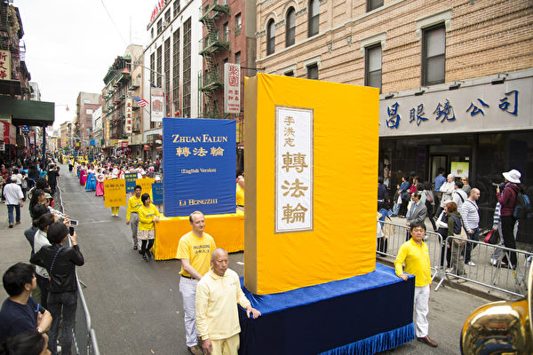 2013年5月18日，紐約曼哈頓，來自世界各地的法輪功學員在此舉行慶祝法輪大法弘傳21周年大遊行。圖為遊行的第一主題「大法洪傳」方陣。圖為《轉法輪》大型書模型。（戴兵／大紀元）