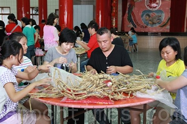 草龙制作师傅钟邦虎(左3)用稻草指导乡亲制作云火龙。(摄影:许享富/大纪元) 草龙制作师傅钟邦虎(左3)用稻草指导乡亲制作云火龙。(摄影:许享富/大纪元)