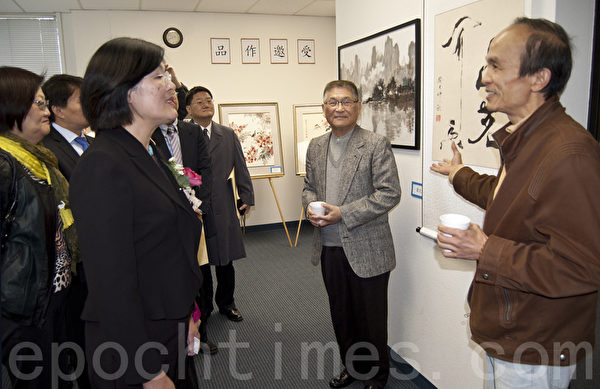 圣地亚哥北郡文教中心汉字文化节书法国画展上,萧昆(右一)向观众介绍他的书法作品《品茗闻香》。在朋友家燃香饮茶时得到的刹那灵感,他将“闻”字写出“香烟缭绕、清静飘逸”的意境。(杨婕/大纪元) 圣地亚哥北郡文教中心汉字文化节书法国画展上,萧昆(右一)向观众介绍他的书法作品《品茗闻香》。在朋友家燃香饮茶时得到的刹那灵感,他将“闻”字写出“香烟缭绕、清静飘逸”的意境。(杨婕/大纪元)