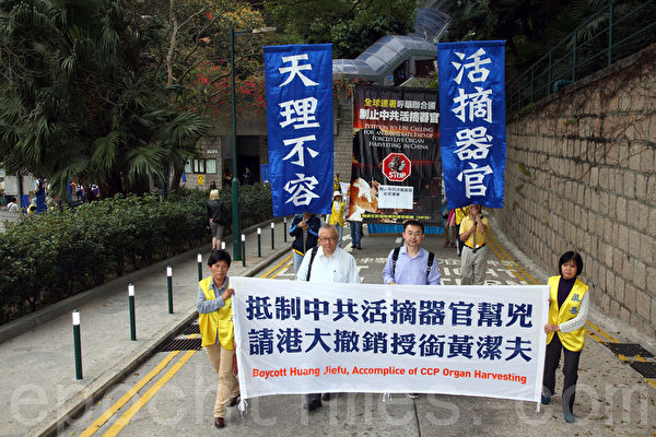 法輪功學員在港大正門外掛起揭露黃潔夫的橫額,引來不少學生觀看。(潘在殊/大紀元) 法輪功學員在港大正門外掛起揭露黃潔夫的橫額,引來不少學生觀看。(潘在殊/大紀元)