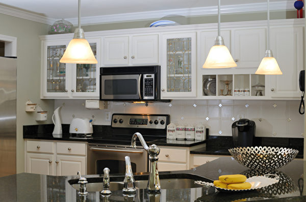 白色的橱柜表现出厨房的整洁，同时白色也可以起到放大空间的作用；黑色的台面让厨房显露出低调的华丽；暖黄的灯光让人有种温暖的家的感觉。(图/Fotolia)
