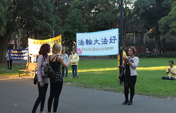 墨尔本来的三位游客,其中一位母亲特别感兴趣法轮功功法,在那里比划法轮功学员动作,在炼功队伍前留影。(骆亚/大纪元) 墨尔本来的三位游客,其中一位母亲特别感兴趣法轮功功法,在那里比划法轮功学员动作,在炼功队伍前留影。(骆亚/大纪元)