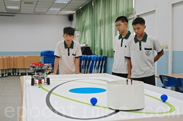 国中竞赛组第一名的三位男生在教室操作机器人,他们分别是:林翌志(中)、方翰毅(左1)、陈昱廷(右1)。(许享富 /大纪元) 国中竞赛组第一名的三位男生在教室操作机器人,他们分别是:林翌志(中)、方翰毅(左1)、陈昱廷(右1)。(许享富 /大纪元)
