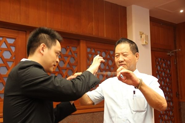黃信凱(左)表演魔術 橡皮筋逃脫。右 議長 陳文昌。(謝月琴/大紀元) 黃信凱(左)表演魔術 橡皮筋逃脫。右 議長 陳文昌。(謝月琴/大紀元)