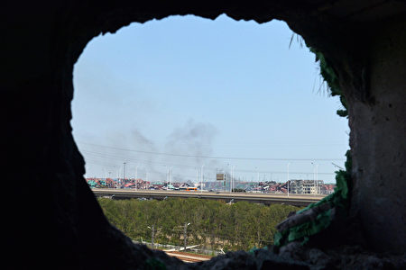 8月18日，天津下了一场大雨，一周前的危险化工品爆炸后的污染问题开始浮现。澳洲昆士兰大学高级研究员的化学专家谢卫国对中共当局的处理生态危机的措施极为忧心。图为，8月16日，从爆炸中击穿的墙壁看远处的爆炸核心区还冒出烟。（AFP PHOTO）