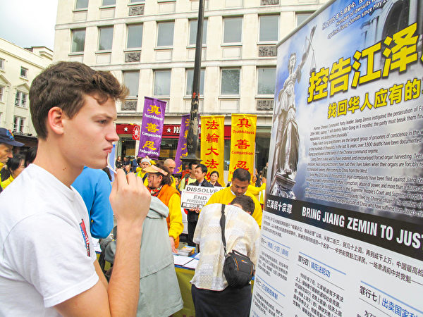图5:二零一五年十月十日,伦敦青年本(Ben)在伦敦圣马丁广场第一次看到法轮功,签名谴责中共活摘罪行后,站在声援控江的真相展板前认真阅读。(明慧网) 图5:二零一五年十月十日,伦敦青年本(Ben)在伦敦圣马丁广场第一次看到法轮功,签名谴责中共活摘罪行后,站在声援控江的真相展板前认真阅读。(明慧网)