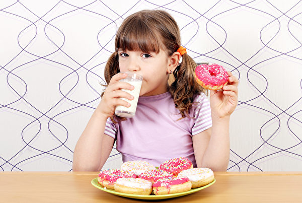小女孩喝牛奶和吃甜甜圈。(Fotolia) 小女孩喝牛奶和吃甜甜圈。(Fotolia)