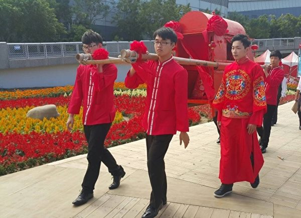 新郎陪在轿子旁迎娶新娘回家。(林宝云/大纪元) 新郎陪在轿子旁迎娶新娘回家。(林宝云/大纪元)