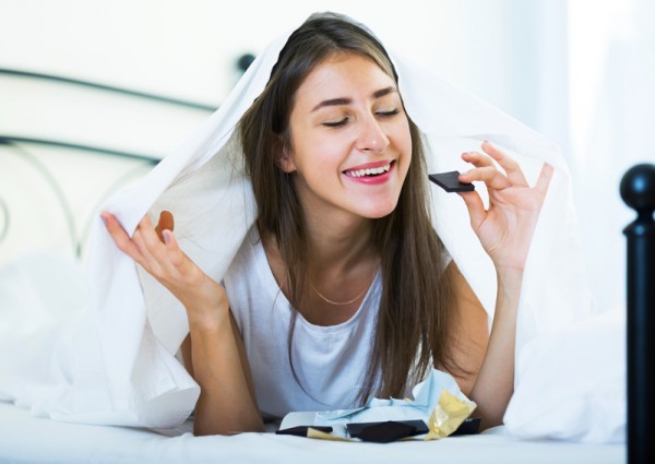 快樂的女孩在床上開心的吃巧克力。(Fotolia) 快樂的女孩在床上開心的吃巧克力。(Fotolia)