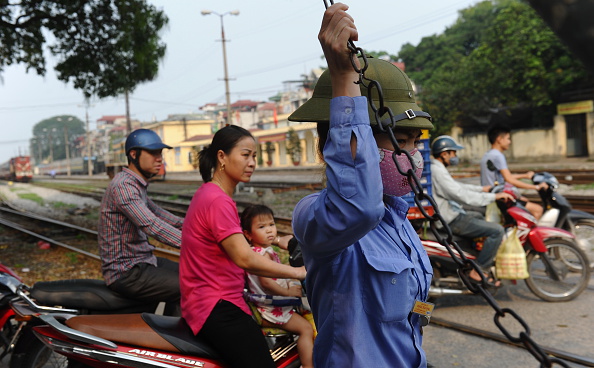 2016年4月,越南河内一铁路工人在铁道口抬起路障,让行人通过.<br /> (HOANG DINH NAM/AFP/Getty Images)