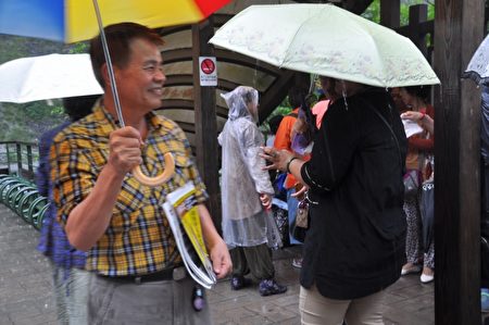 法轮功学员童石海(黄格上衣),夫妻俩不论刮风下雨,都开着车到太鲁阁长春祠发资料给陆客及劝三退。(詹亦菱/大纪元)