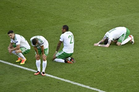 Dejected Northern Ireland players rest on the pitch after loosing 0-1 in a own goal during the Euro 2016 round of sixteen football match Wales vs Northern Ireland, on June 25, 2016 at the Parc des Princes stadium in Paris. / AFP / PHILIPPE LOPEZ (Photo credit should read PHILIPPE LOPEZ/AFP/Getty Images)