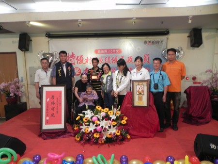嘉義縣長張花冠〈左3〉頒獎表揚新港鄉侍奉殘障母親〈坐輪椅者〉至孝的孝行楷模洪新景〈右6〉。(蔡上海/大紀元)