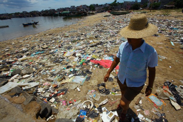 This photo taken on June 13, 2011shows a Chinese farmer walking along the rubbish-strewn beach along the sea coast in Anquan village, south China's Hainan province. China suffers from widespread water pollution after years of unbridled economic growth. According to government data, more than 200 million Chinese currently do not have access to safe drinking water. CHINA OUT AFP PHOTO (Photo credit should read STR/AFP/Getty Images)