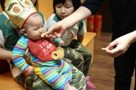 由長輩擦拭寶寶嘴邊的口水,邊說祝福的吉祥話。(傳藝中心提供)