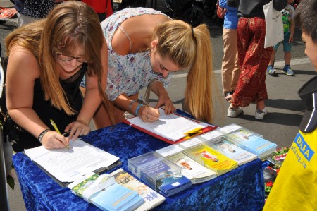 两位年轻女士在征签表上签名，支持法轮功学员。（金湖/大纪元）