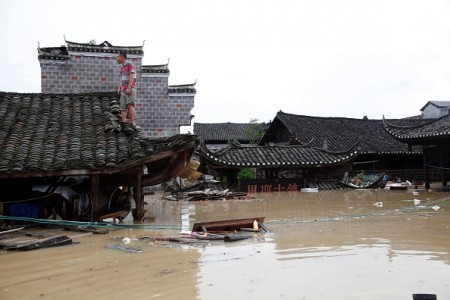 This photo taken on June 21, 2016 shows a man standing on the rood of a flood-inundated building in the flooded ancient town of Longshan county, central China's Hunan province. Heavy rains have left 22 people dead and 15 others missing in south China since June 18, the State Flood Control and Drought Relief Headquarters (SFDH) said on June 20. / AFP / STR / China OUT (Photo credit should read STR/AFP/Getty Images)