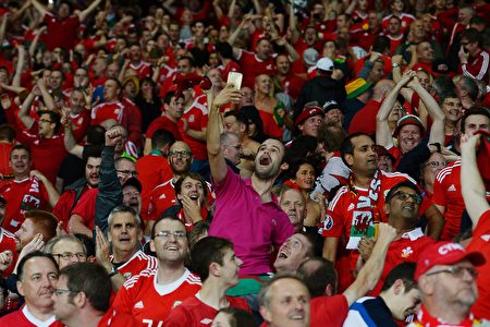 Wales supporters celebrate at the end of the Euro 2016 quarter-final football match between Wales and Belgium at the Pierre-Mauroy stadium in Villeneuve-d'Ascq near Lille, on July 1, 2016. / AFP / MIGUEL MEDINA (Photo credit should read MIGUEL MEDINA/AFP/Getty Images)