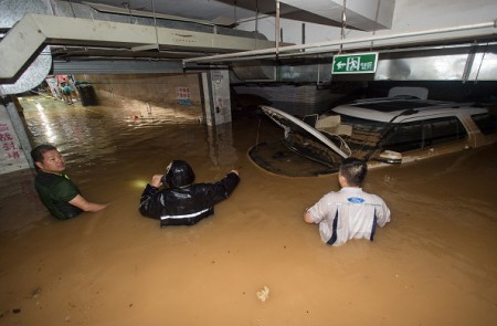 TOPSHOT - This picture taken on July 2, 2016 shows people trying to remove a car from a flooded parking garage in Wuhan, in China's central Hubei province. Authorities on July 2 issued an orange alert for heavy rain expected in central and southern parts of China in the coming days. / AFP / STR / China OUT (Photo credit should read STR/AFP/Getty Images)