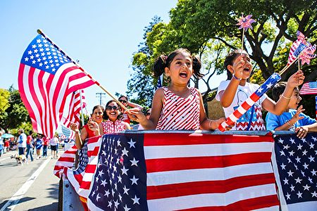 People wave American flags as they ride through 4th of July Parade in Alameda, California on Monday, July 4, 2016. / AFP / GABRIELLE LURIE (Photo credit should read GABRIELLE LURIE/AFP/Getty Images)