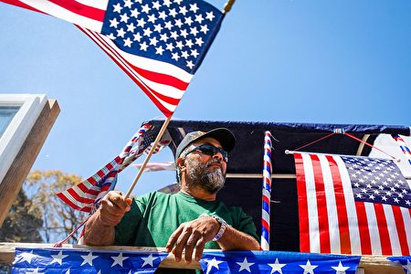 A man waves an American flag from a float during the 4th of July Parade in Alameda, California on July 4, 2016. / AFP / GABRIELLE LURIE (Photo credit should read GABRIELLE LURIE/AFP/Getty Images)