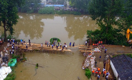 Chinese soldiers and workers try to repair a collapsed dam along the Xiangyang River in Xinji Village in Yangzhou, in east China's Jiangsu province on July 6, 2016. Heavy rain around China's Yangtze river basin has left 128 people dead and scores missing, media said on July 5, with more damage feared from a typhoon expected to land this week. / AFP / STR / China OUT (Photo credit should read STR/AFP/Getty Images)