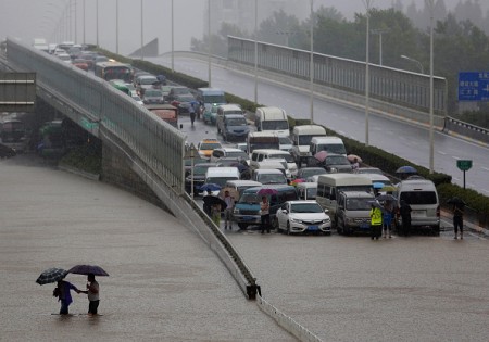 WUHAN, CHINA - JULY 06: Local Chinese residents walk on a flooded street in heavy rain in Wuhan £¬Hubei province, China.6 July 2016. An overnight storm following days of rain has stopped traffic, cut power and water supplies and trapped citizens in their homes in many parts of Wuhan, a metropolis on the Yangtze River. The downpour caused severe waterlogging as rivers, lakes and reservoirs of the city have swollen, leading to closure of a tunnel across the Yangtze as well as some subway stations and underground passages, according to local traffic authorities. From 8 p.m. of Tuesday (5 July 2016) to 8 a.m. of Wednesday, the precipitation of the city proper reached 180 millimeters and the district of Caidian received 206 millimeters of rain.> on July 6, 2016 in Wuhan, China. (Photo by Wang He/Getty Images)