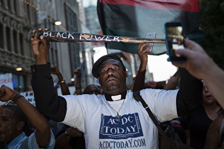 A man holds a bat reading "Black Power" during a protest in Dallas, Texas, on Thursday, July 7, 2016 to protest the deaths of Alton Sterling and Philando Castile. Black motorist Philando Castile, 32, a school cafeteria worker, was shot at close range by a Minnesota cop and seen bleeding to death in a graphic video shot by his girlfriend that went viral Thursday, the second fatal police shooting to rock America in as many days. / AFP / Laura Buckman (Photo credit should read LAURA BUCKMAN/AFP/Getty Images)
