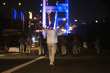A man approaches Turkish military with his hands up at the entrance to the Bosphorus bridge in Istanbul on July 16, 2016. Turkish security forces on July 15 partially shut down the two bridges across the Bosphorus Strait in Istanbul. Turkish military forces on July 16 opened fire on crowds gathered in Istanbul following a coup attempt, causing casualties, an AFP photographer said. / AFP / Bulent KILIC AND GURCAN OZTURK (Photo credit should read BULENT KILIC,GURCAN OZTURK/AFP/Getty Images)