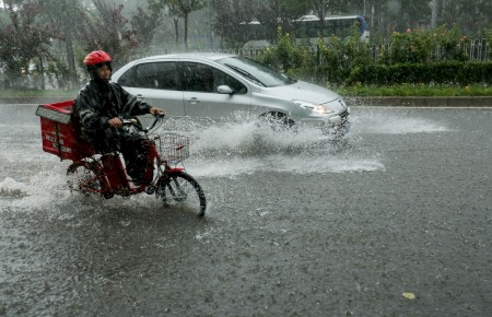7月20日北京街頭,暴雨中的摩托車和汽車。(STR/AFP/Getty Images)