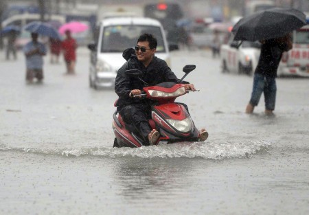 7月20日北京街頭,一個男子開車摩托車涉水前行。(STR/AFP/Getty Images)