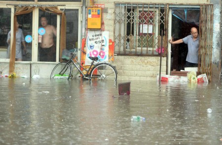7月20日,北京居民看著屋外的洪水。(STR/AFP/Getty Images)