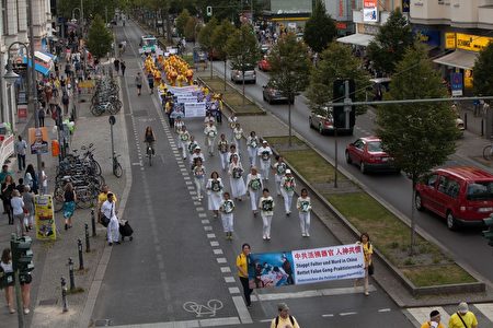 7月30日，法輪功學員在柏林舉行大型遊行活動。圖為身穿白色衣褲的學員手捧被迫害致死的學員的照片走過柏林大街。（Jason Wang／大紀元）