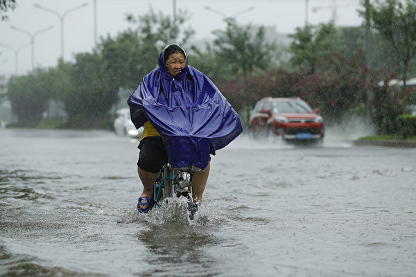 2016年7月20日，一名妇女在北京洪水肆虐的街道上骑车。 (Lintao Zhang/Getty Images)