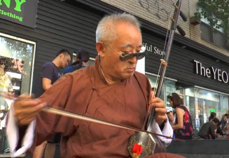 在纽约法拉盛街头卖艺的原中央广播艺术团二胡演奏家辛修禄。 (韩瑞／新唐人)