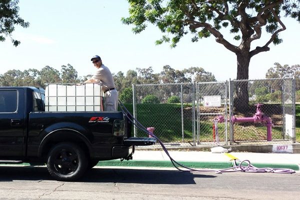 圖：2016年7月30日，聖地亞哥市供水區首次為居民客戶提供免費循環水（Recycled Water），用以清洗庭院、澆灌植物、洗車等，但不能做為飲用水。圖為一名居民將從紫色水管流出的循環水裝入卡車上的巨大容器。（聖地亞哥市公共事業部提供）