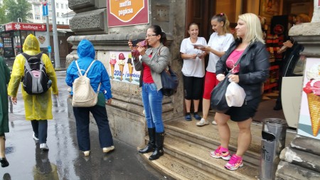 路邊避雨的民眾,忙著看真相資料、拍照。(大紀元)
