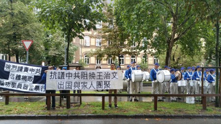 小帥哥前,「抗議中共阻撓王治文出國與家人團聚」的橫幅聲援王治文。(大紀元)