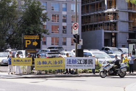 蒙特利尔法轮功学员在国际会展中心附近举着横幅传递讯息。(易柯 / 大纪元)