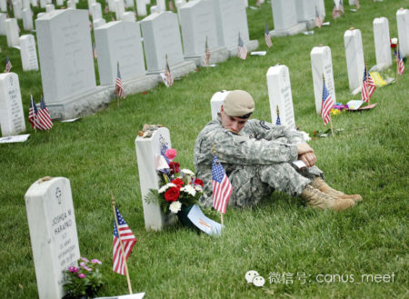 A soldier sits at a grave in Section 60 of Arlington National Cemetery May 25, 2009 in Arlington, Virginia. Section 60 is one of the main places where those who died while serving in the wars in Iraq and Afghanistan are buried. (Photo by Brendan Smialowski/Getty Images)