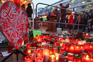 BERLIN, GERMANY - DECEMBER 22: Visitors walk past a makeshift memorial at the reopened Breitscheidplatz Christmas market only a short distance from where three days ago a truck plowed into the market, killed 12 people and injured dozens in a terrorist attack on December 22, 2016 in Berlin, Germany. The Breidscheidplatz Christmas market is reopening today, though its small amusement rides and bright lights displays will remain shut off in a sign of continuing mourning for the attack victims. Meanwhile police have launched a European-wide manhunt for Anis Amri, a 24-year-old Tunisian man they suspect of having driven the truck. (Photo by Sean Gallup/Getty Images)